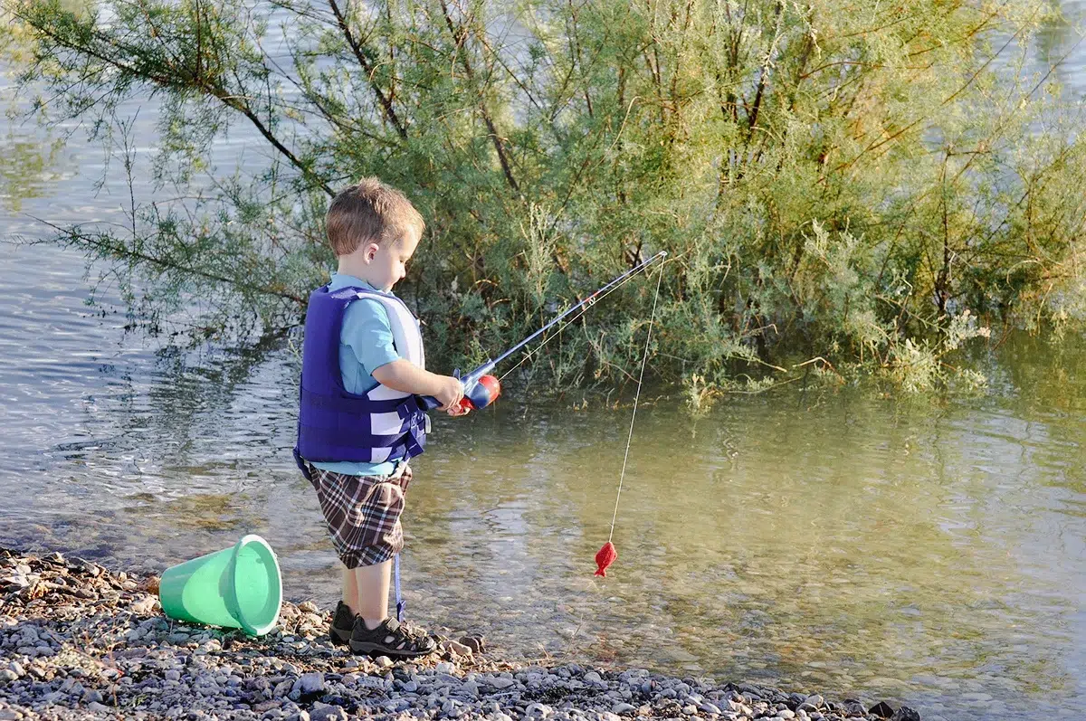 Junge Junge fischt am See Bourg en Bresse